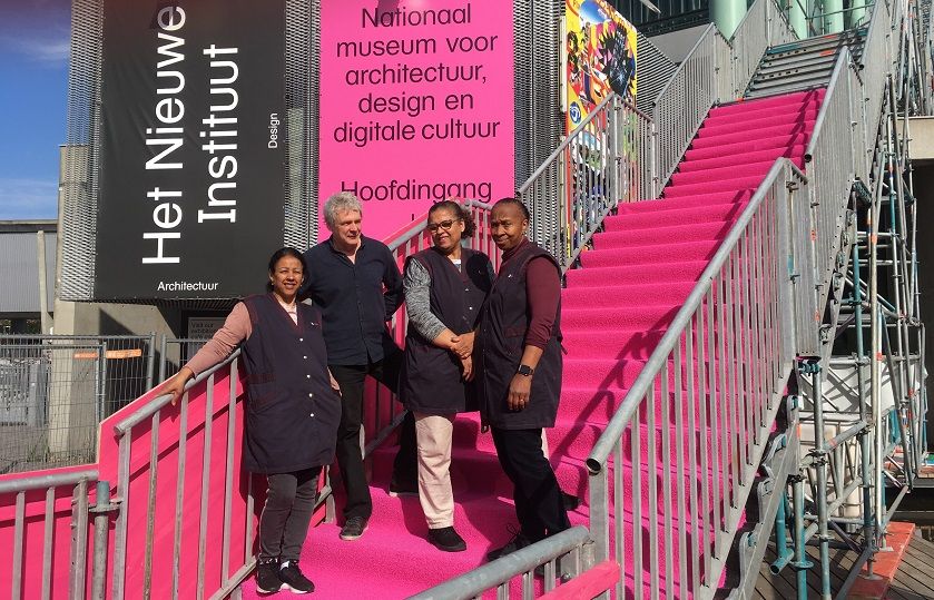 Joost de Munk van Het Nieuwe Instituut staat met 3 schoonmakers van Gom op een stellagetrap met roze bekleding, die naar het dak van het museum gaat.
