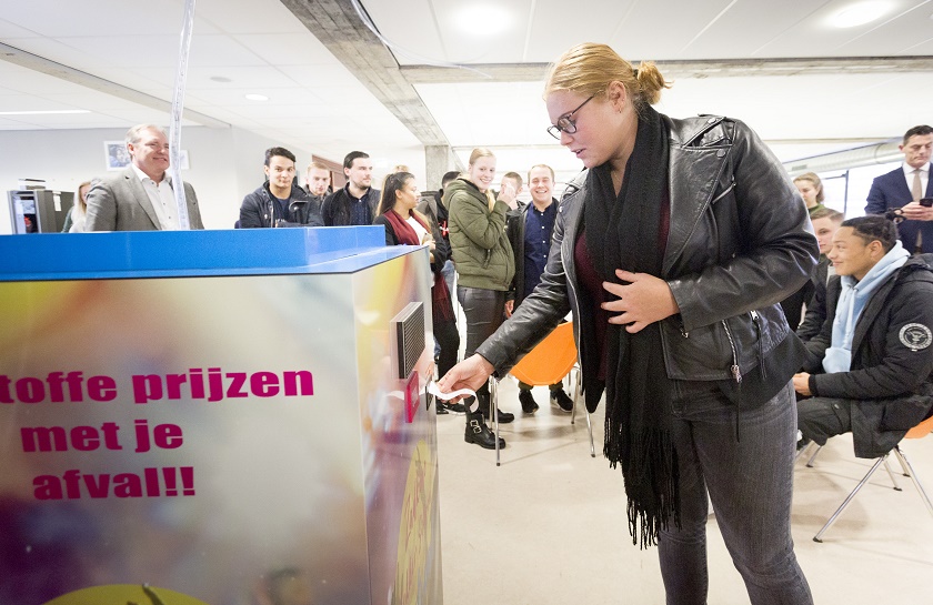een studente haalt haar tegoedbonnetje uit de interactieve afvalbak, op de achtergrond zitten meerdere andere studenten