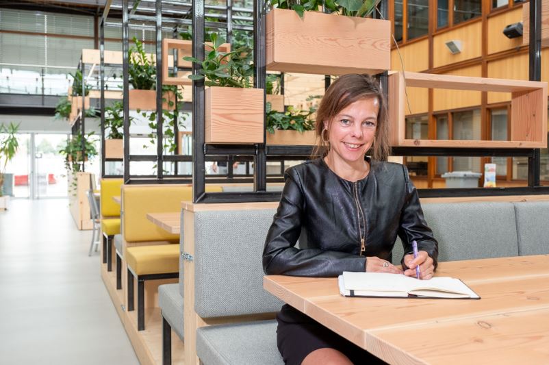 Juliette Sprongers schrijft in haar schrift en kijkt in de camera.