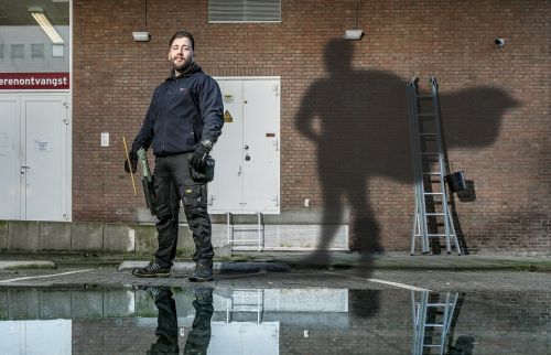 Gom Uitblinker 4-2020 Luciano Scheffer poseert tegen de gevel van het pand waar hij de ramen was, met als schaduw een superman op de muur geprojecteerd