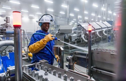 een man van Kleentec reinigt met een hogedrukspuit een machine uit de voedingsmiddelenindustrie