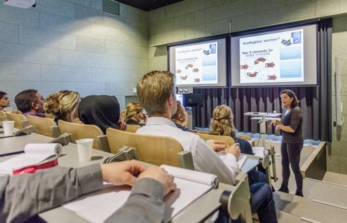 medewerkers van Gom Zorg zitten te luisteren naar docent infectiepreventie