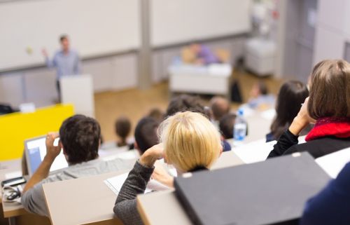 studenten volgen de les in een lokaal met 'theateropstelling', beneden staat de docent te vertellen