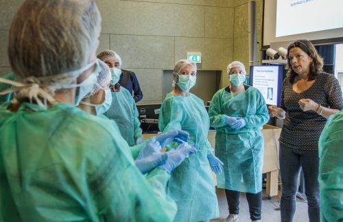 medewerkers van Gom Zorg leren hoe zij beschermende kleding aan moeten trekken