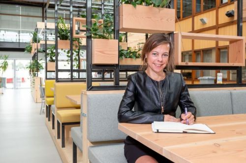 Juliette Sprongers schrijft in haar schrift en kijkt in de camera.