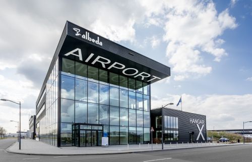 de buitenkant van het leslocatie van Albeda op Rotterdam The Hague Airport; door de ramen zie je de voorkant van een vliegtuig