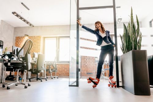 Vrouw in zakelijke kleding rolt op rollerskates binnen op kantoor.