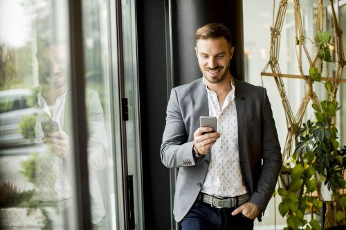 Medewerker die al lopende op zijn telefoon kijk die hij in zijn hand heeft.