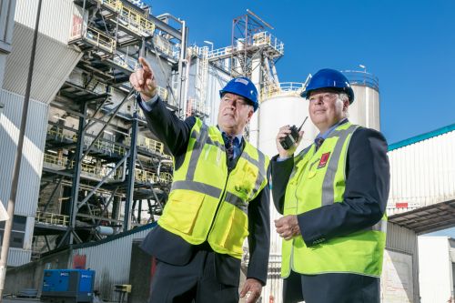 Een beveiligingsmedewerker die een collega met portofoon op een industrieterrein instructie geeft.