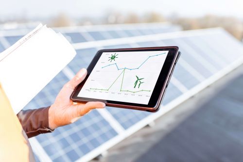 Facilitair medewerker op dak met zonnepanelen waar tablet rendement weergeeft