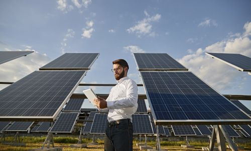 Medewerker energiemanagement analyseert data op tablet staand naast veld met zonnepanelen