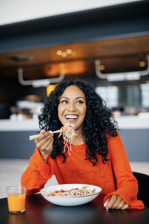 Vrouw geniet van gezonde lunch met noedels Food&i