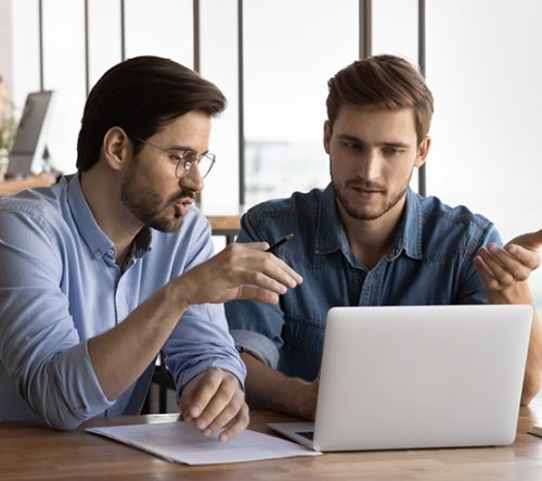 Twee collega's bekijken en bespreken tijdlijn routekaart op laptop