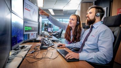 Twee centralisten bekijken de inkomende meldingen op het beeldscherm op de AlarmServiceCentrale.