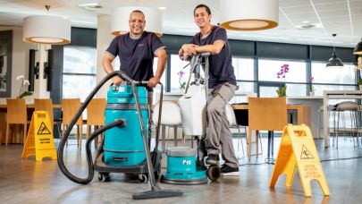 2 medewerkers van Gom Specialistische Reiniging poseren met een waterzuiger en boenmachine 2 medewerkers van Gom Specialistische Reiniging poseren met een waterzuiger en boenmachine