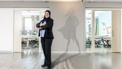 Gom Uitblinker 3-2020 Yamina Massoudi poseert in haar werkomgeving in het ziekenhuis, met als schaduw een superwoman op de muur geprojecteerd