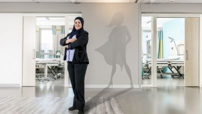 Gom Uitblinker 3-2020 Yamina Massoudi poseert in haar werkomgeving in het ziekenhuis, met als schaduw een superwoman op de muur geprojecteerd