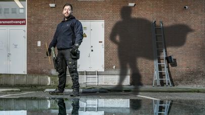 Gom Uitblinker 4-2020 Luciano Scheffer poseert tegen de gevel van het pand waar hij de ramen was, met als schaduw een superman op de muur geprojecteerd
