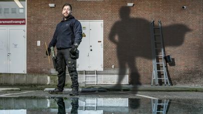 Gom Uitblinker 4-2020 Luciano Scheffer poseert tegen de gevel van het pand waar hij de ramen was, met als schaduw een superman op de muur geprojecteerd