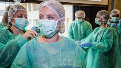 medewerkers van Gom Zorg oefenen met het op de juiste manier aantrekken van beschermende kleding, schort, mondkapje en haarnet