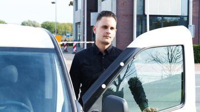 Mannelijke mobiele surveillance medewerker staat bij auto voor een gebouw. De beveiliger staat op het punt om in de auto te stappen en naar de volgende melding toe te rijden. Mannelijke mobiele surveillance medewerker staat bij auto voor een gebouw. De beveiliger staat op het punt om in de auto te stappen en naar de volgende melding toe te rijden.