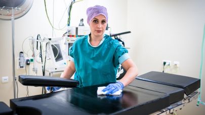 een medewerkster van Gom Zorg maakt de operatietafel schoon in een operatiekamer