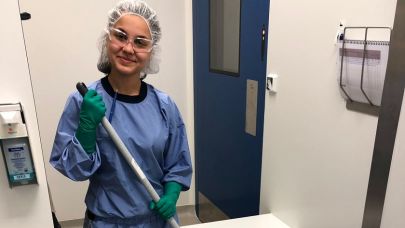 een schoonmaakmedewerkster van Gom Zorg staat in een voorportaal met een stofwisser in haar handen