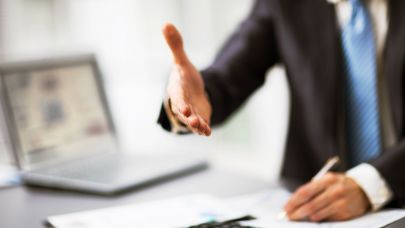 Man in zakelijke kleding steekt hand uit naar zijn gesprekspartner.