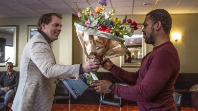 business unit directeur Richard de Maar overhandigd Gom Uitblinker Edman Janga een bos bloemen