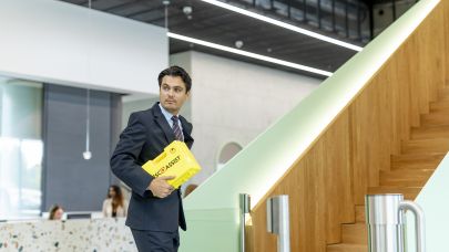 Mannelijke Embracemedewerker die een geel koffertje vast heeft. Mannelijke Embracemedewerker die een geel koffertje vast heeft.
