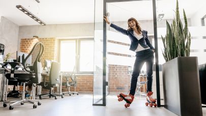 Vrouw in zakelijke kleding rolt op rollerskates binnen op kantoor.