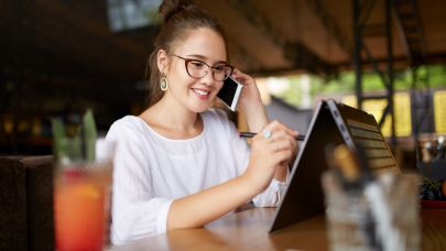 Vrouw is aan het telefoneren en tevens aan het werk achter haar laptop