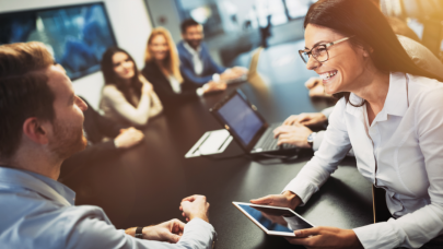 Groep collega's die met veel enthousiasme vergaderen aan een lange vergadertafel