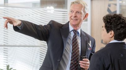 Mannelijke beveiliger in uniform helpt mannelijke bezoeker opweg met de juiste wandelroute naar zijn bestemming binnen het kantoorpand. 
