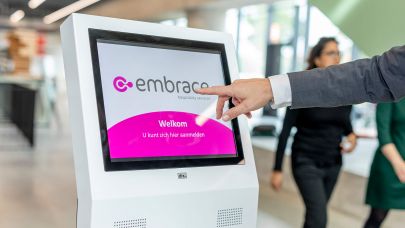 Hand reikt uit naar aanmeldpilaar waarop het logo van Embrace staat vertoond.