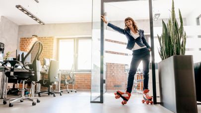 Vrouw in zakelijke kleding rolt op rollerskates binnen op kantoor.
