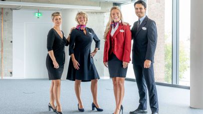 Drie vrouwelijke receptionisten en een gastheer staan geposeerd voor de camera in hun uniformen.