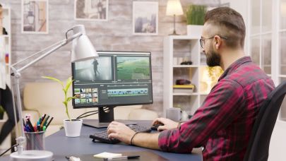 Man zit achter zijn bureau en is een video aan het bewerken op zijn computer