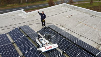 Sander Henten zwaait lachend in de camera terwijl hij op een dak met behulp van de solar max zonnepanelen reinigt.