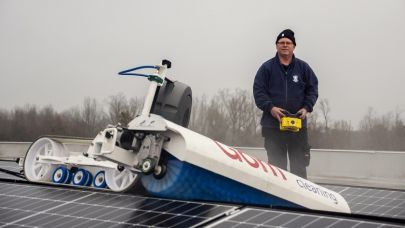 Sander Henten staat op een dak en reinigt met behulp van de solar max zonnepanelen 