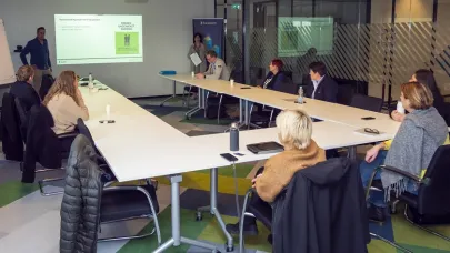 een groep zit aan tafels opgesteld in een u-vorm en luisteren naar de trainer