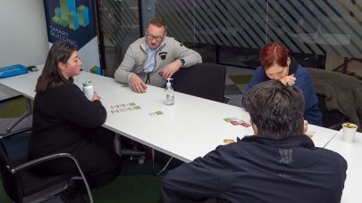 vier cursisten zitten aan tafel en doen een oefening met kaarten