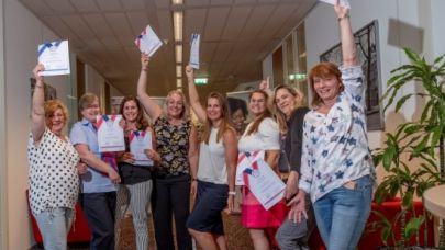Een groepje rayonleiders van Gom Amsterdam houden vol trots hun certificaat omhoog.