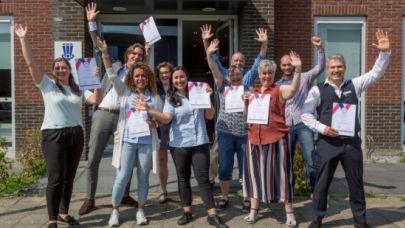 Een groepje rayonleiders van Gom Breda houden vol trots hun certificaat omhoog.