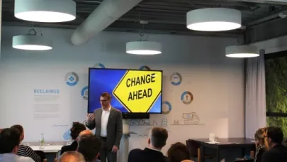 Spreker geeft presentatie voor een groep mensen met op het scherm de tekst 'Change Ahead