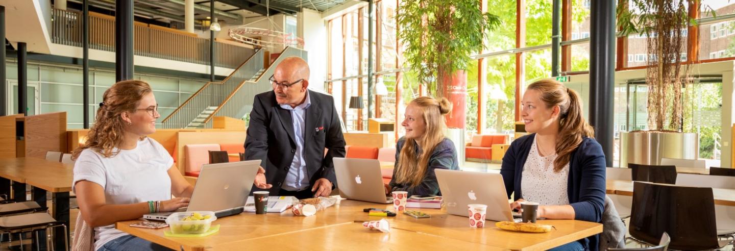 Studenten aan tafel in gesprek met medewerker van Gom