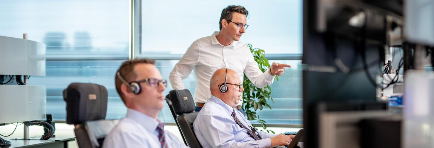 Twee mannen kijken op een computerscherm om op afstand bruggen, wegen en sluizen te bedienen.