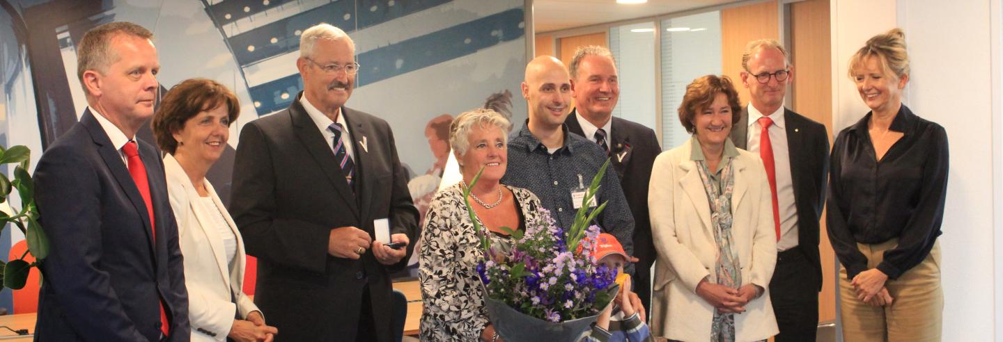 Vijf mannen en vier vrouwen staan op het hoofdkantoor van Trigion met elkaar op de foto om het jubileum van een medewerker te vieren.