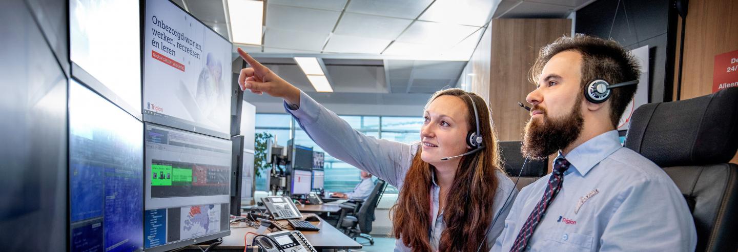 Twee centralisten bekijken de inkomende meldingen op het beeldscherm op de AlarmServiceCentrale.