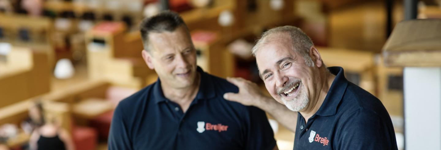 Twee mannen die lachend aan het werk zijn.